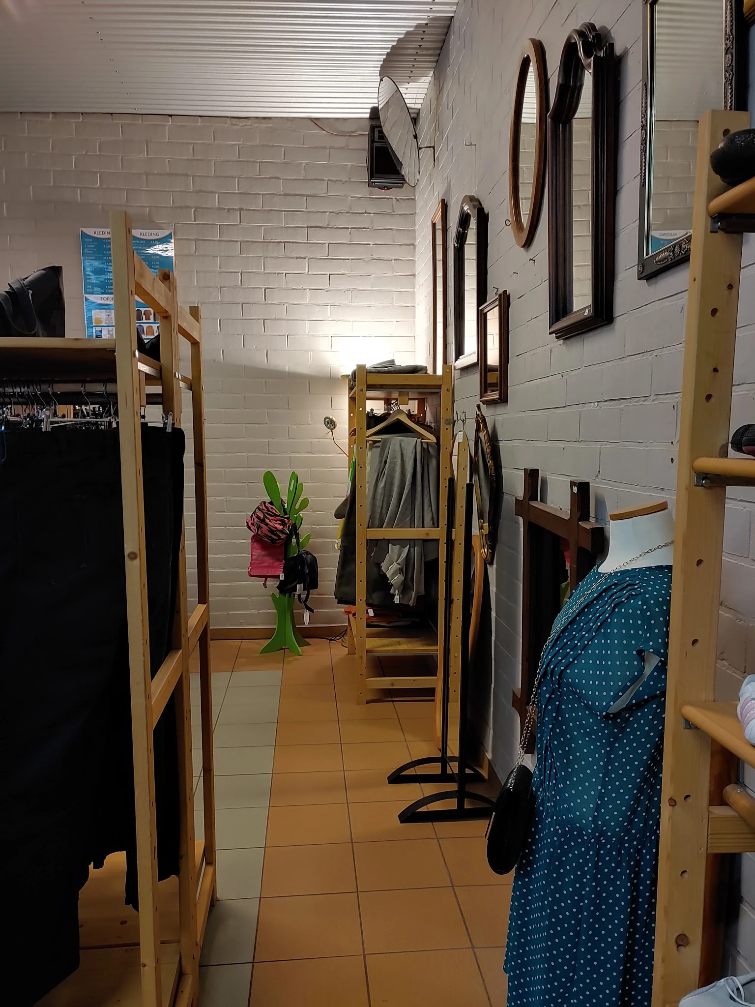 Winkelinterieur met houten stellingen en kledingrekken vol tweedehands kleding