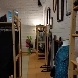 Winkelinterieur met houten stellingen en kledingrekken vol tweedehands kleding