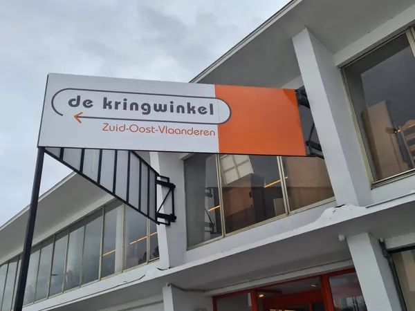 Wit gebouw met oranje winkelbordje 'de kringwinkel' en pijl naar Zuid-Oost-Vlaanderen