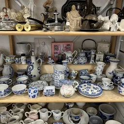 Schatten in kast met serviesgoed, borden, kopjes en decoratieve items in blauw-wit porselein
