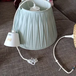 Lichtblauwe stoflampenkapje met plooien en witte snoer op grijze stof