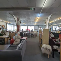 Ruime winkelvloer met meubels, boekenkasten en diverse tweedehands artikelen uitgestald
