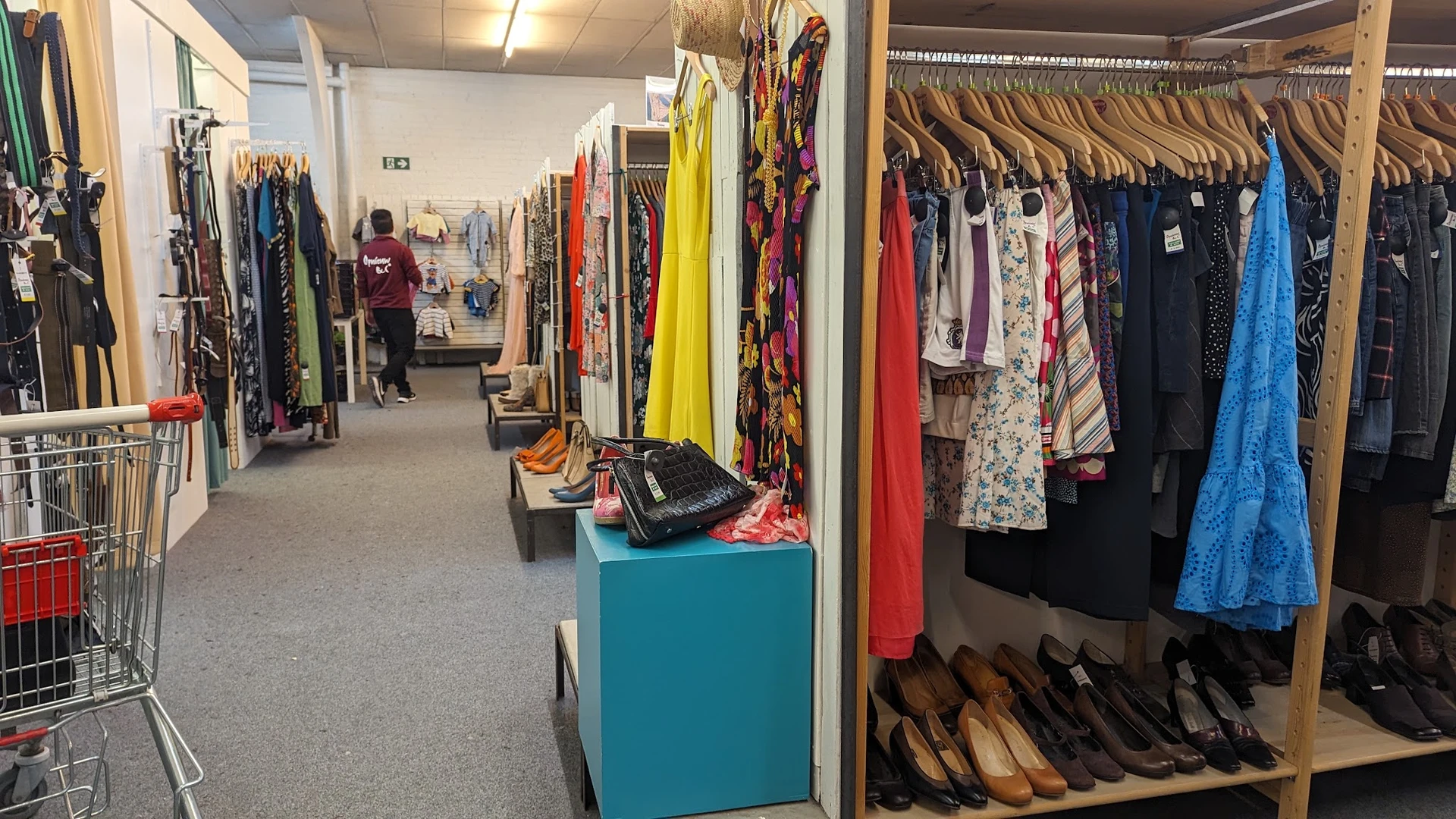 Winkelvloer met kledingrekken, schoenen en accessoires in een kringloopwinkel