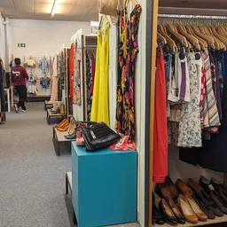 Winkelvloer met kledingrekken, schoenen en accessoires in een kringloopwinkel