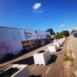 Voorgevel van kringloopwinkel Opnieuw & Co aan de straat met witte plantenbakken ervoor