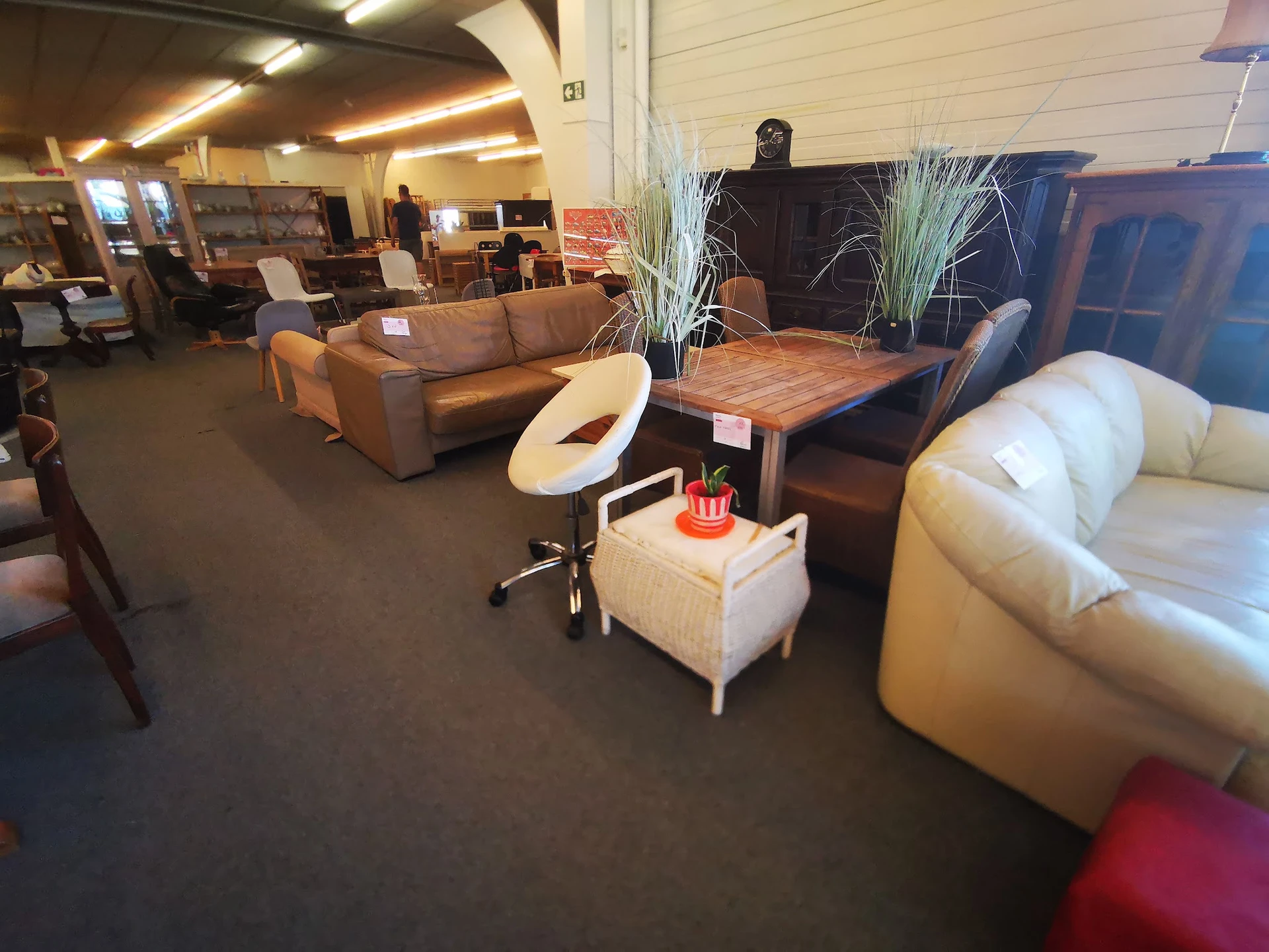 Winkelvloer met uitgestalde meubels: bruine bank, witte fauteuil, houten tafel en witte poef met decoraties