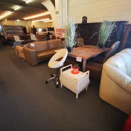 Winkelvloer met uitgestalde meubels: bruine bank, witte fauteuil, houten tafel en witte poef met decoraties