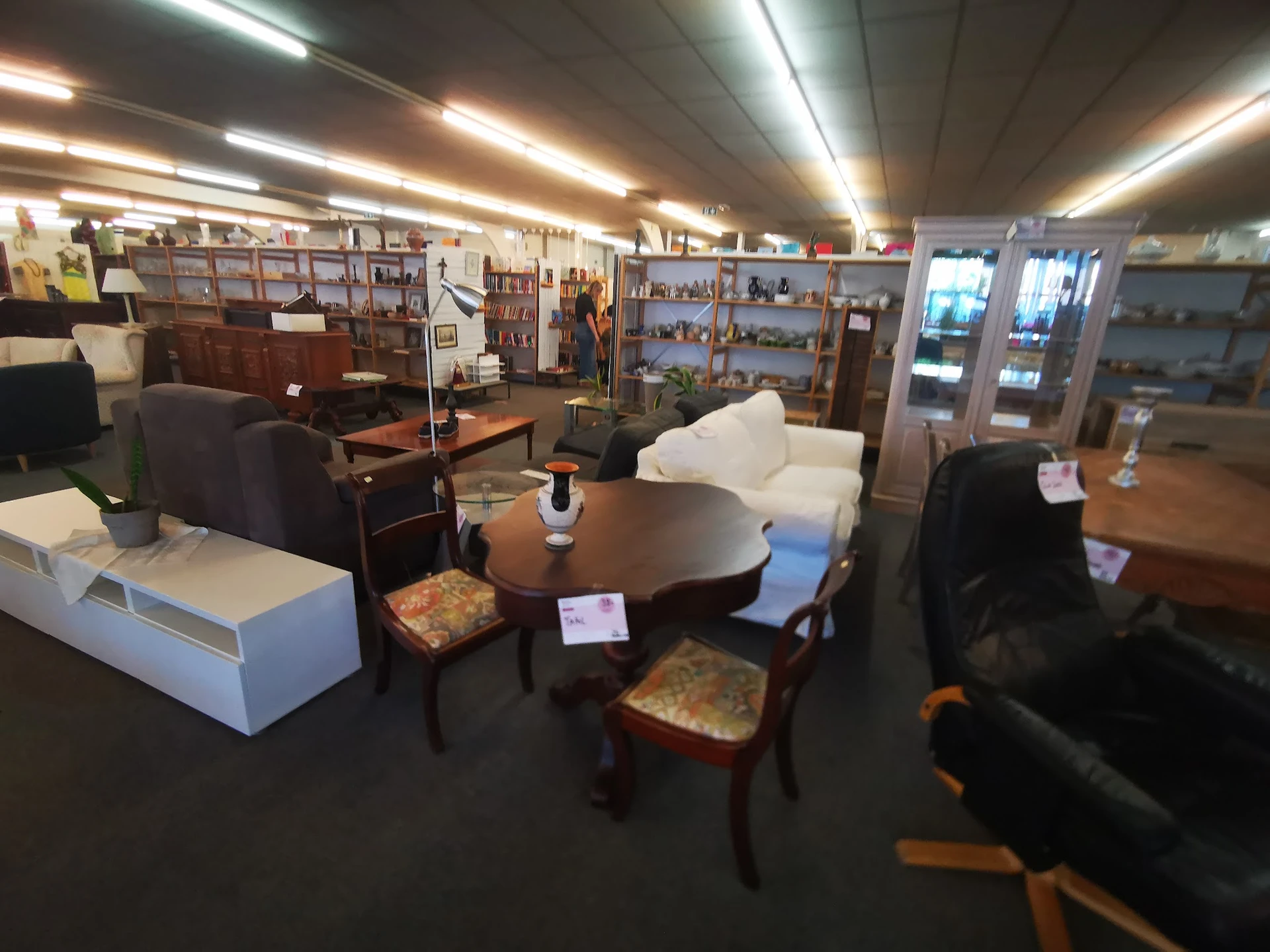 Winkelvloer met zithoeken, stoelen, tafels en vitrinekast met huisraad en decoratie