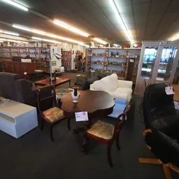 Winkelvloer met zithoeken, stoelen, tafels en vitrinekast met huisraad en decoratie