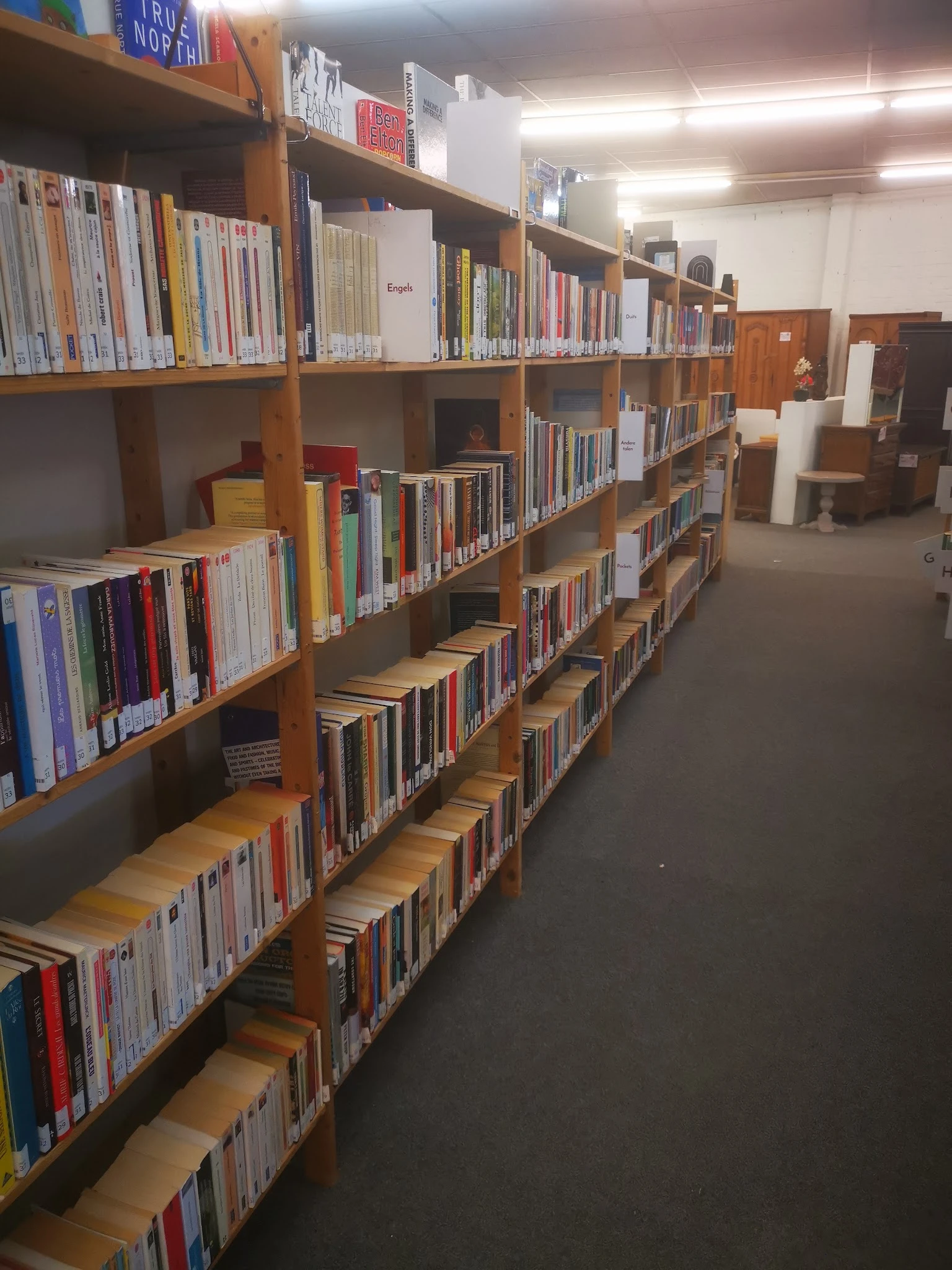 Houten boekenrekken met cd's en dvd's in een kringloopwinkel