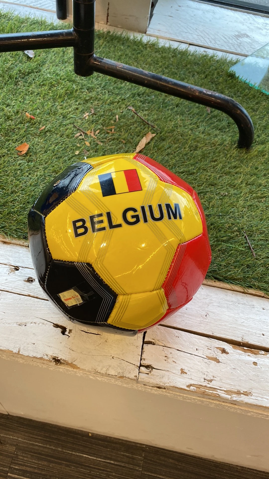 Gele voetbal met Belgische vlag en opschrift 'BELGIUM' op houten oppervlak