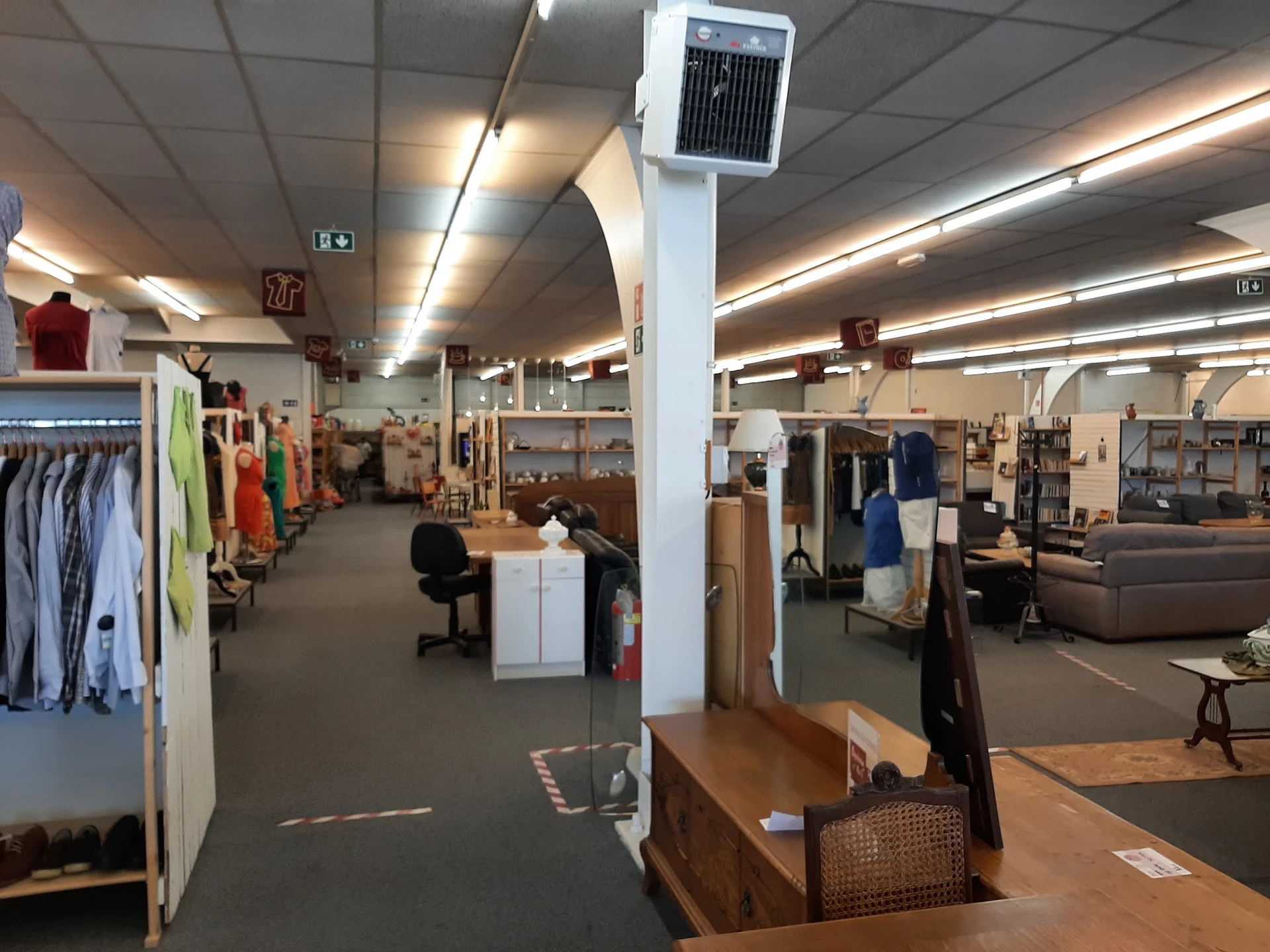 Winkelinterieur met kledingrekken, meubels en diverse tweedehandsartikelen langs de wanden en in het midden