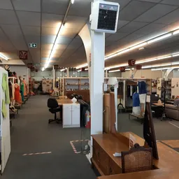 Winkelinterieur met kledingrekken, meubels en diverse tweedehandsartikelen langs de wanden en in het midden