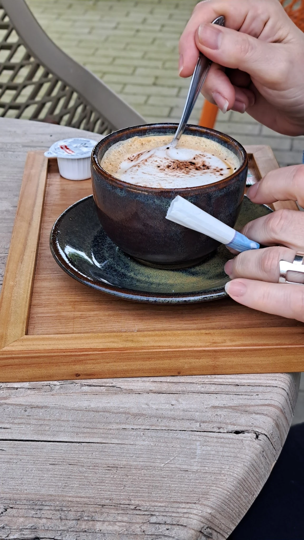 Close-up van een donkere keramische kop met schotelrand en cacao-drank, hand markeert onderkant met pen