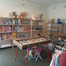 Winkelbinnenkant met boekenrekken, speelgoed, kinderkledingrek en een tafelvoetbalspel