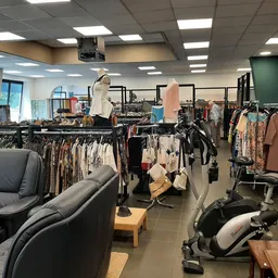 Winkelvloer met kledingrekken, fauteuils, boekenkast en fitnessequipment in tweedehands winkel