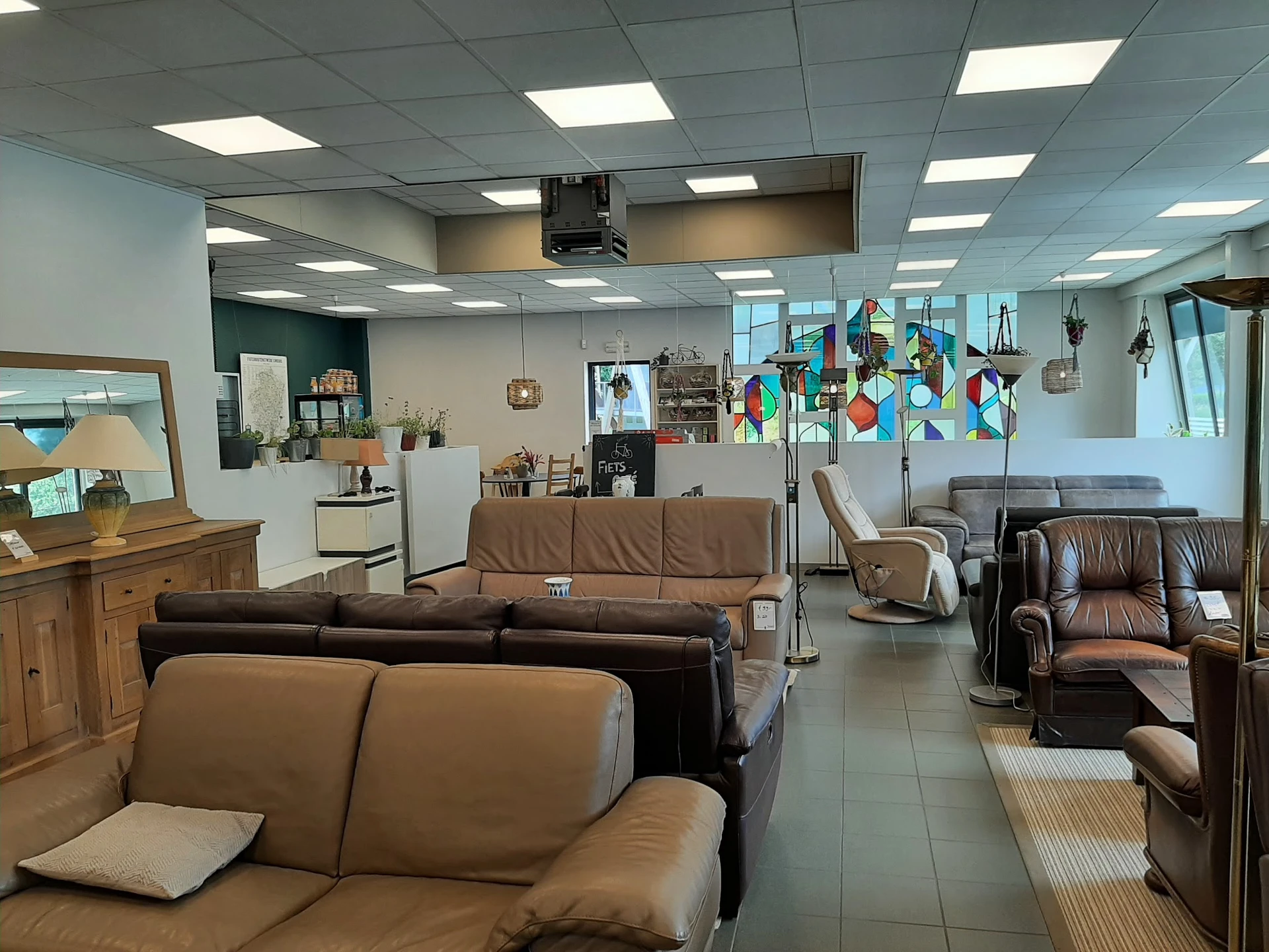 Winkelvloer met bruine leren zitmeubels en fauteuils, stellingen en inrichting van een kringloopwinkel