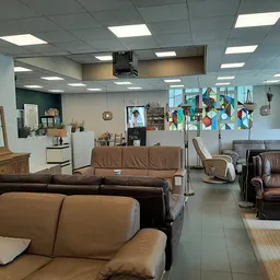 Winkelvloer met bruine leren zitmeubels en fauteuils, stellingen en inrichting van een kringloopwinkel