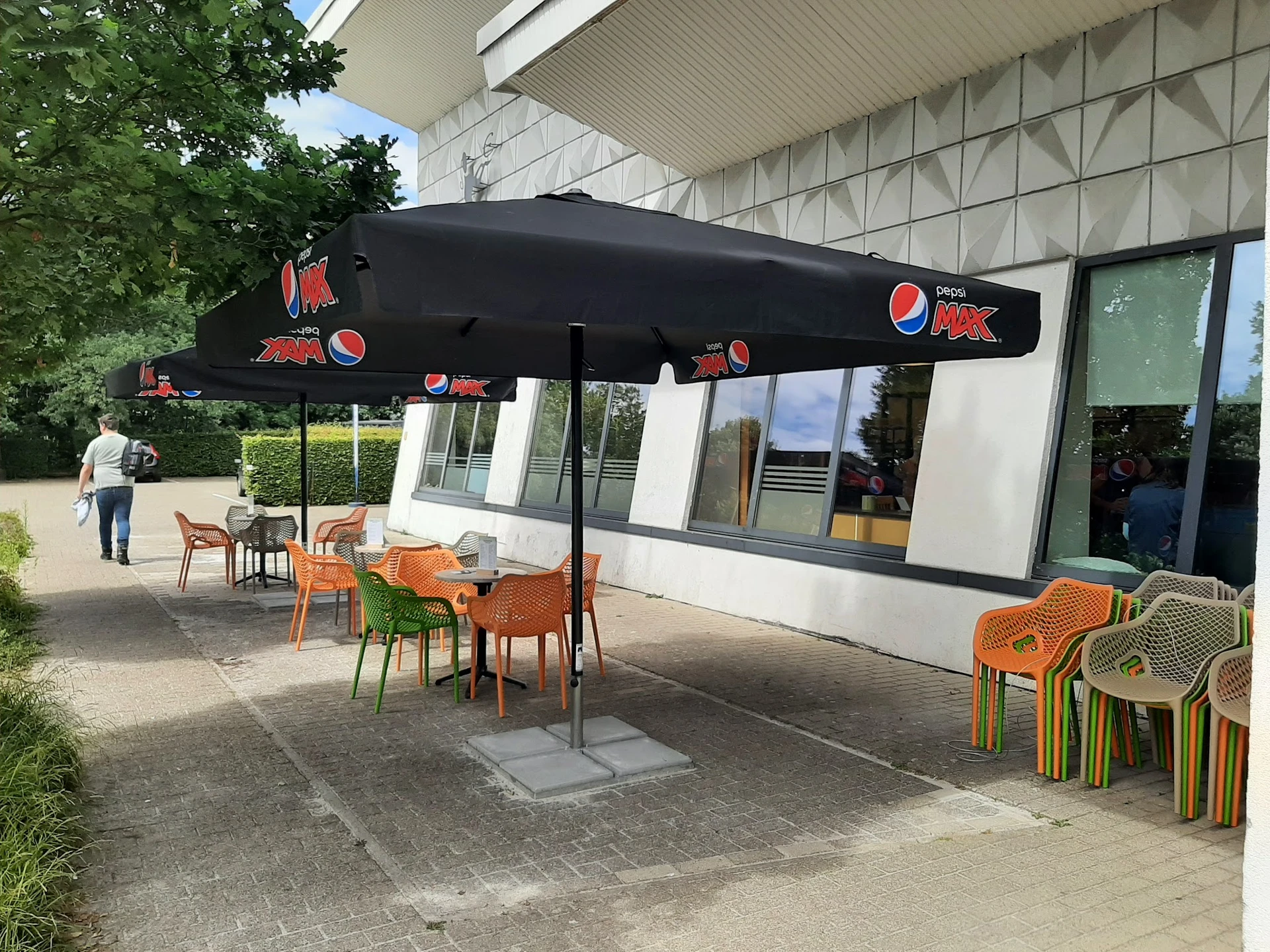 Terras met zwarte parasol en oranje stoelen voor een moderne gevel