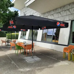Terras met zwarte parasol en oranje stoelen voor een moderne gevel