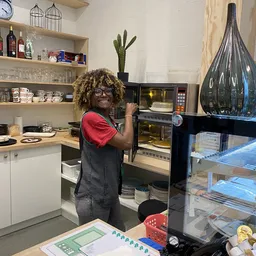 Medewerker in rode shirt en schort poseert bij professionele ovens in de keuken
