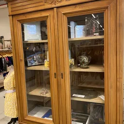 Glazen displaykasten met houten frames, gevuld met decoratieve voorwerpen en vazen