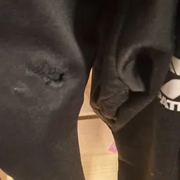 Donkere stoflaag met slijtplekken, mogelijk van kledingstuk of meubelstof