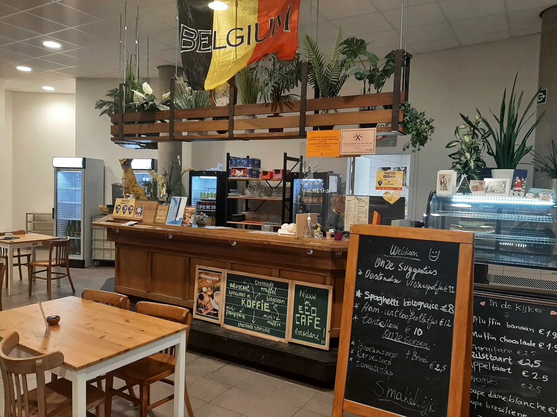 Binnenaanzicht van een lunchcafé met toonbank, menu op krijtbord en houten tafels met stoelen