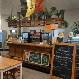 Binnenaanzicht van een lunchcafé met toonbank, menu op krijtbord en houten tafels met stoelen