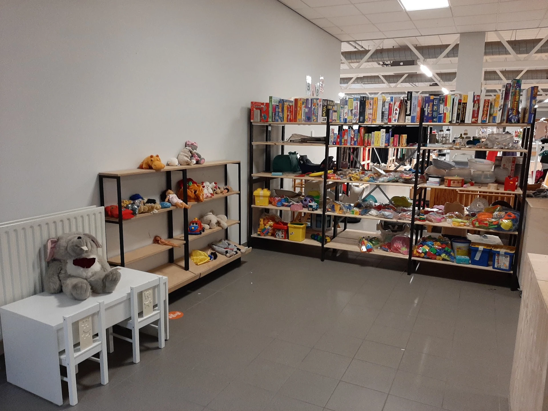 Winkelinterieur met speelgoed, boeken en huishoudartikelenop stellingen en tafels