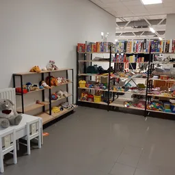 Winkelinterieur met speelgoed, boeken en huishoudartikelenop stellingen en tafels