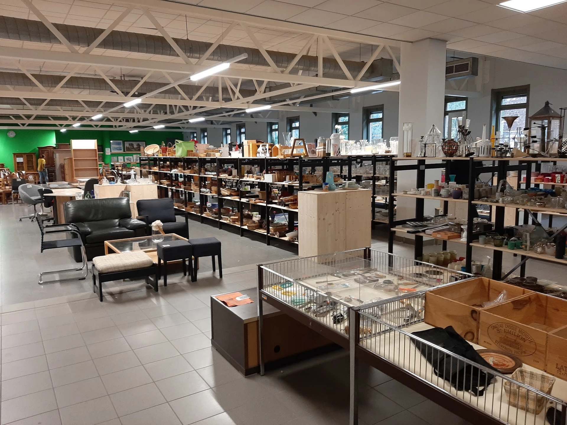 Ruim winkelinterieur met stellingen, meubels en huishoudspullen uitgestald in verschillende afdelingen