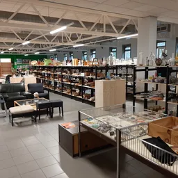Ruim winkelinterieur met stellingen, meubels en huishoudspullen uitgestald in verschillende afdelingen