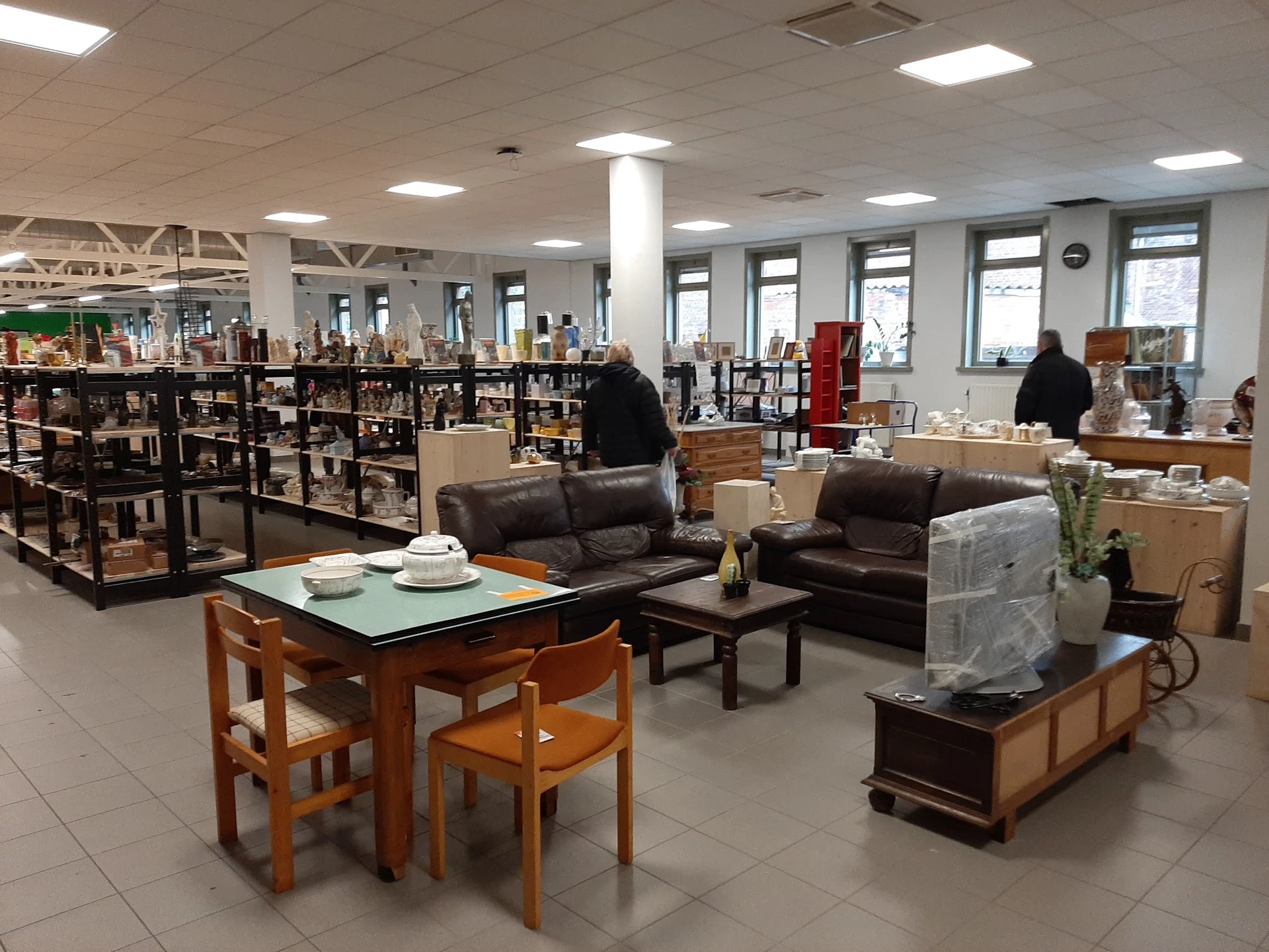 Winkelvloer met bruine leren meubels, houten eettafel met stoelen, boeken in stellingen en grote ramen