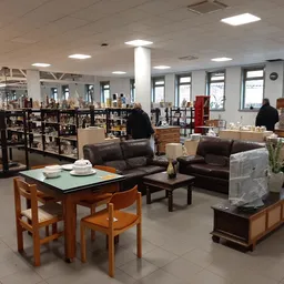 Winkelvloer met bruine leren meubels, houten eettafel met stoelen, boeken in stellingen en grote ramen