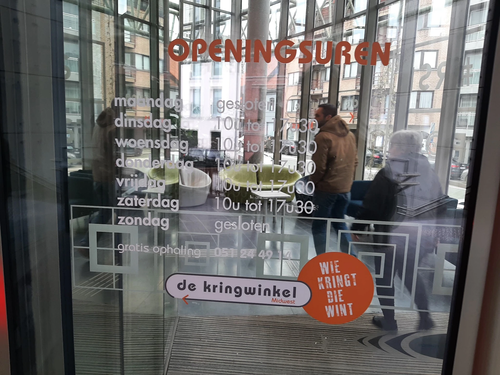 Glazen voorgevel van kringloopwinkel met openingstijden en logo 'de kringwinkel' op raam
