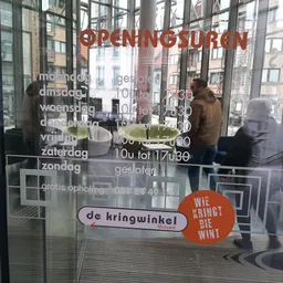 Glazen voorgevel van kringloopwinkel met openingstijden en logo 'de kringwinkel' op raam