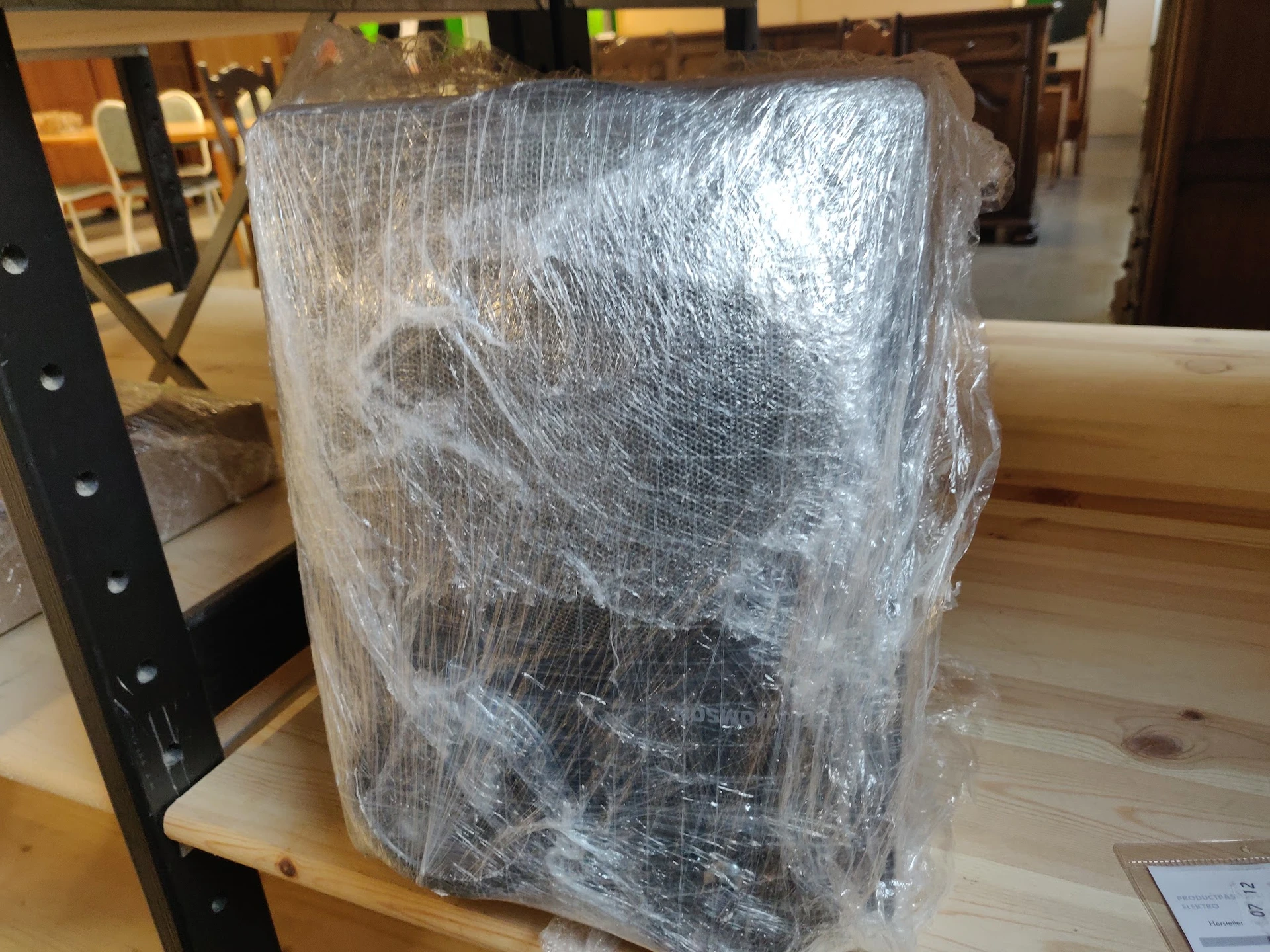 In plastic verpakt meubelstuk of apparaat op houten tafel in winkelinterieur