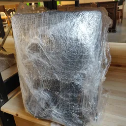 In plastic verpakt meubelstuk of apparaat op houten tafel in winkelinterieur