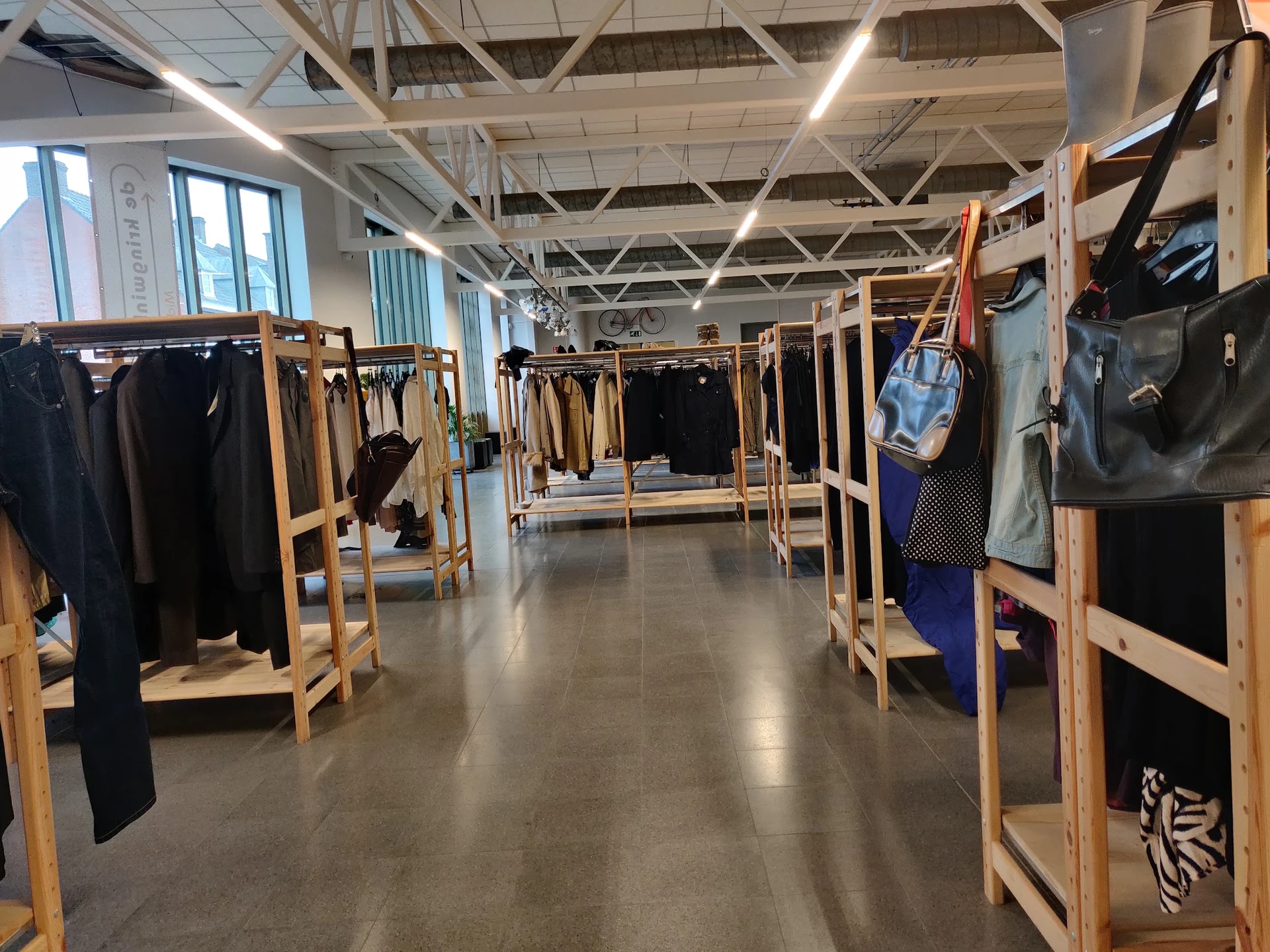 Winkelvloer met houten rekken vol tweedehands kleding langs beide zijden