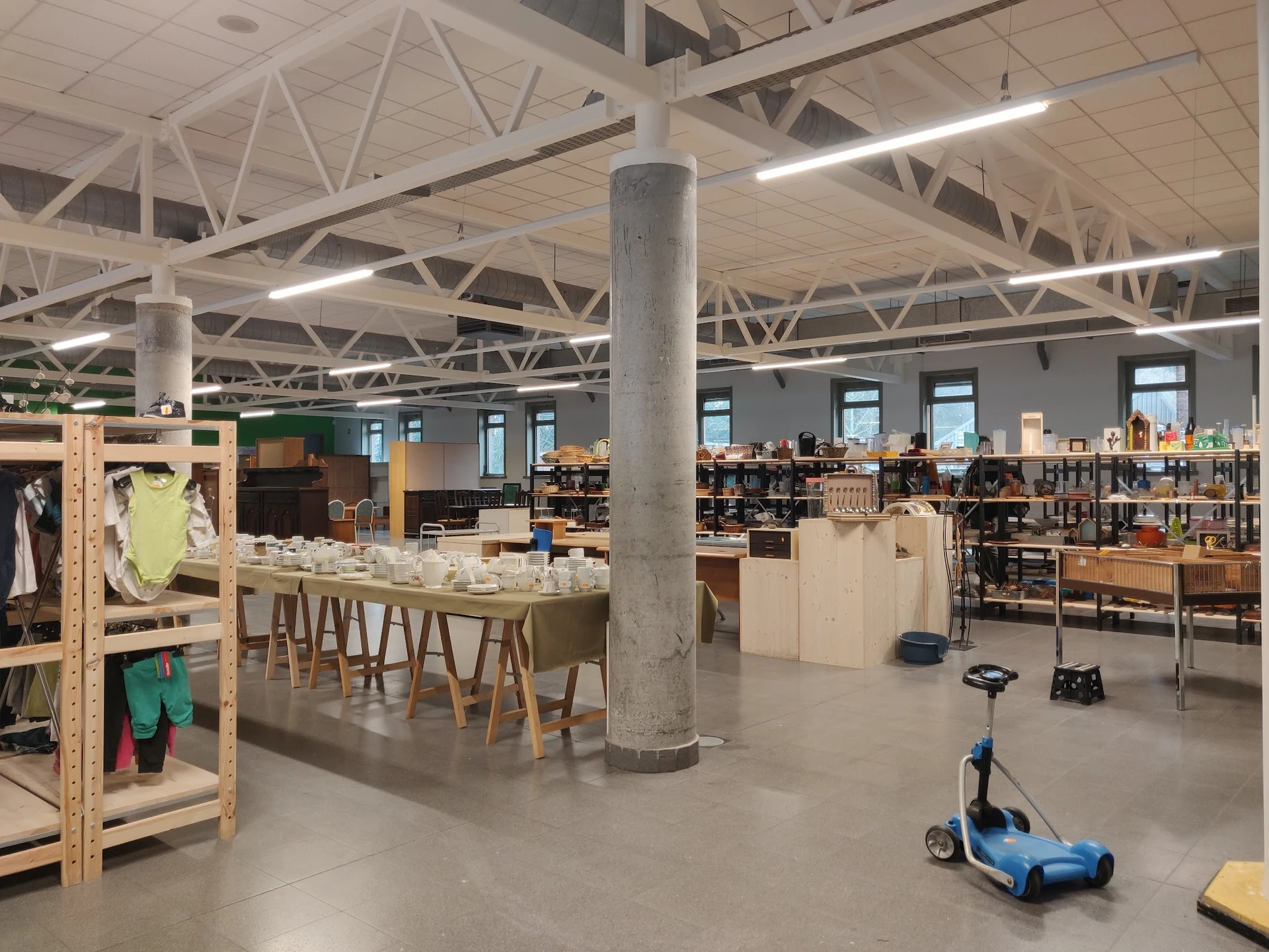 Ruim winkelinterieur met houten meubels, rekken met spullen en speelgoed op de vloer