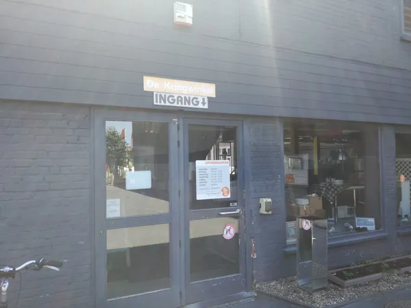 Voorgevel van kringloopwinkel met glazen deur en ramen, INGANG bord zichtbaar