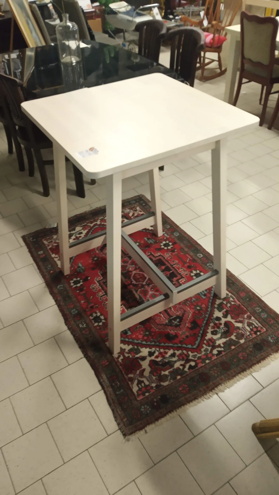 Witte eettafel met stoelen op rode oosterse tapijten op tegelvloer