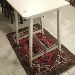Witte eettafel met stoelen op rode oosterse tapijten op tegelvloer