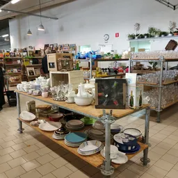 Tafel met uitgestalde serviesgoed, kopjes, borden en andere huishoudelijke artikelen in de kringloopwinkel
