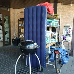 Winkelinterieur met blauwe gordijn, barbecue, stellingen met spullen en diverse tweedehandsartikelen
