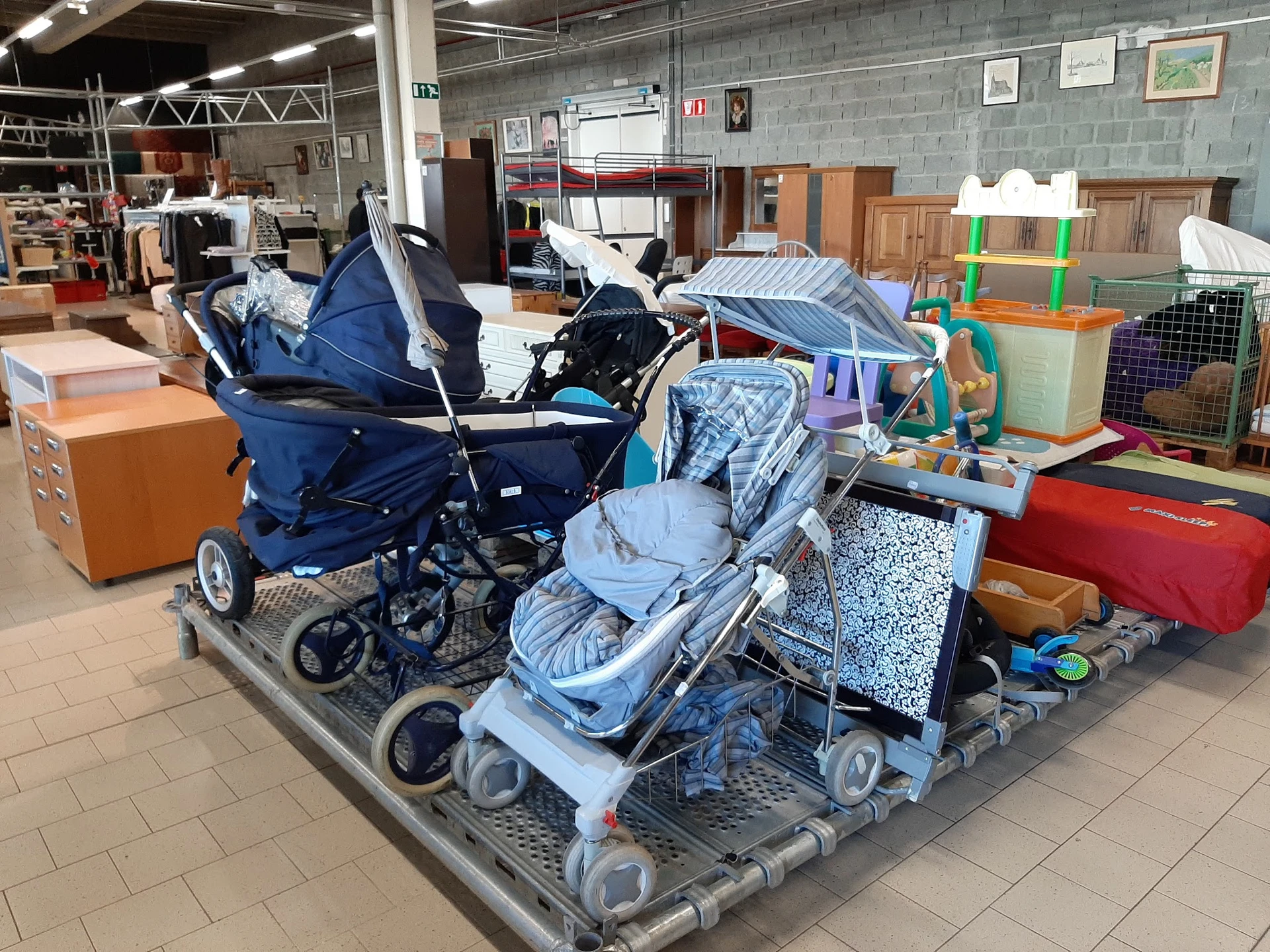 Uitgestalde kinderwagens en babycargos in diverse kleuren op een pallet in de winkel