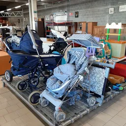 Uitgestalde kinderwagens en babycargos in diverse kleuren op een pallet in de winkel