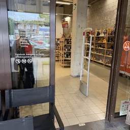 Winkelinterieur met witte stellingen vol spullen, betonnen kolommen en betegelde vloer