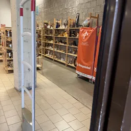 Binnenaanzicht van kringloopwinkel met houten stellingen vol met spullen en oranje boodschappentas